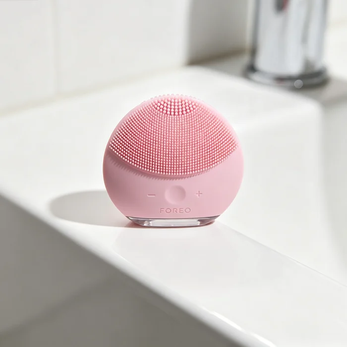a pink Foreo Luna silicone face scrubber on a white bathroom counter