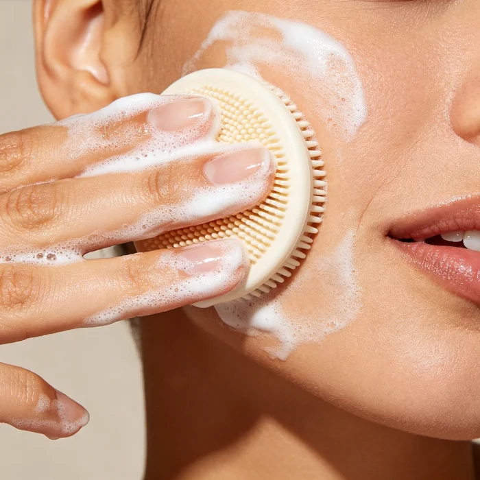 a person applying gentle cleanser to a silicone face scrubber