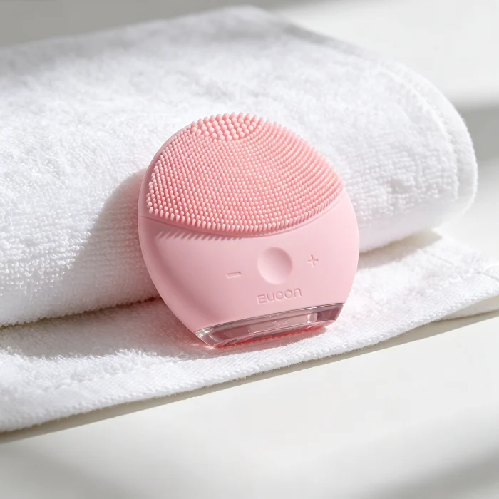 a pink silicone facial brush on a white towel