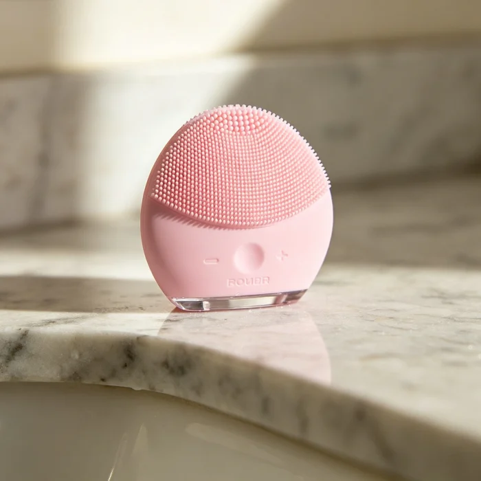 a pink silicone face brush on a bathroom counter